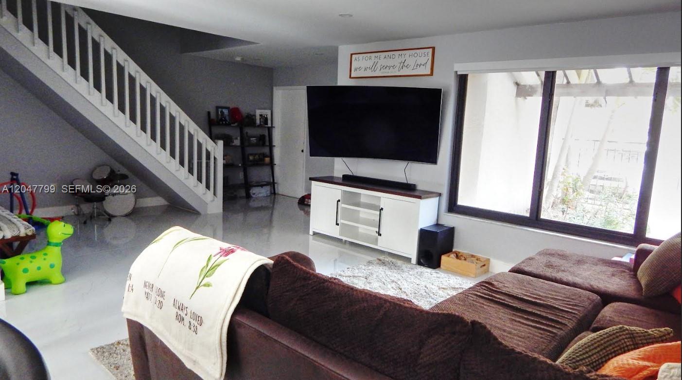 A living room features a large television, a white media console, and a staircase — 10171 SW 137th Ct, Miami FL 33186, MIAMI, FL