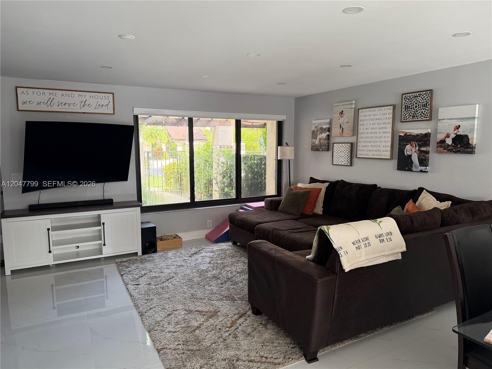 A living room features a large sectional sofa, a television on a white console, and tile flooring — 10171 SW 137th Ct, Miami FL 33186, MIAMI, FL