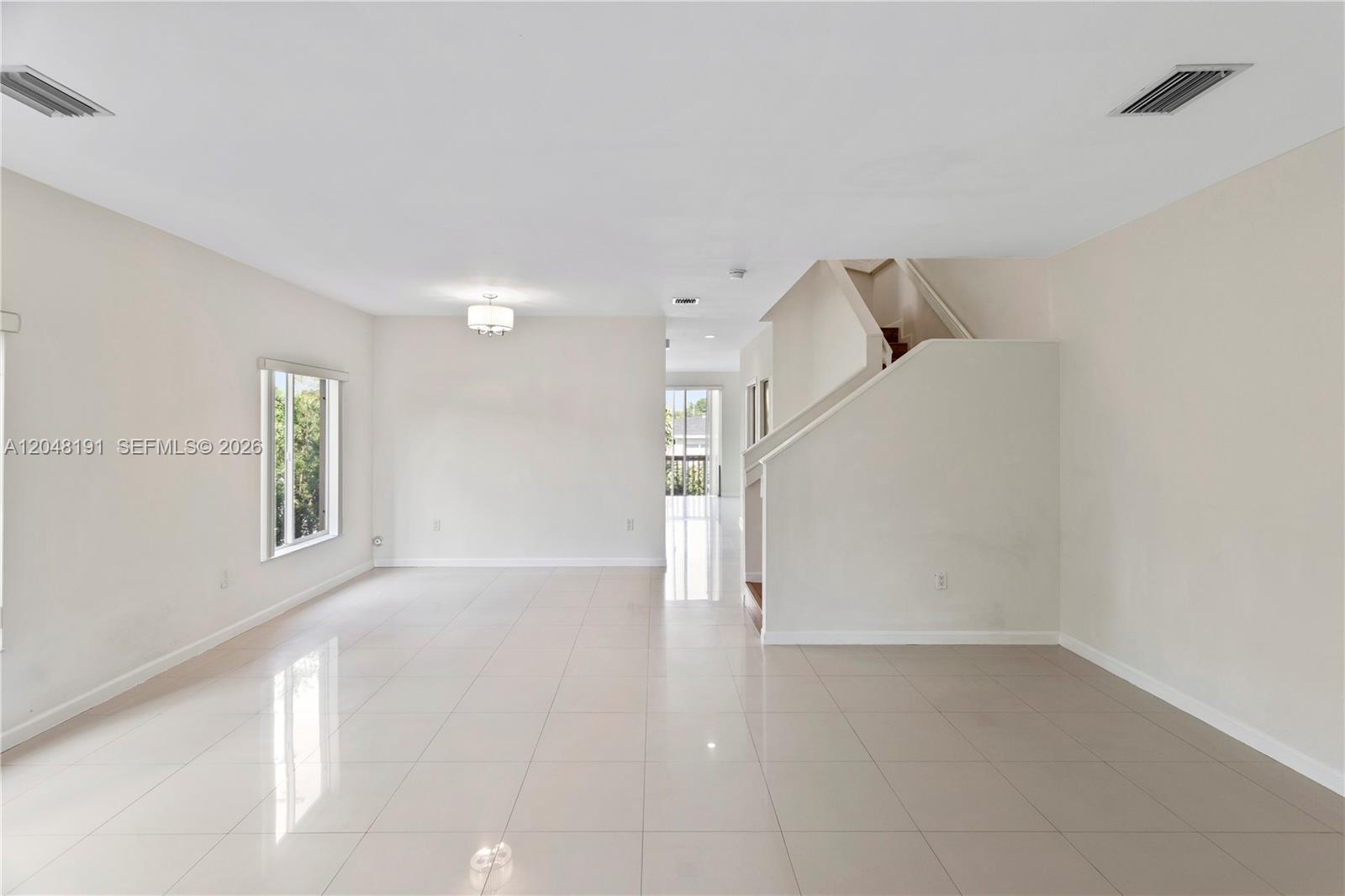 An open living area features white tile flooring, a staircase, and a large window — 2782 SW 33rd Ave # 2782, Miami FL 33133, MIAMI, FL