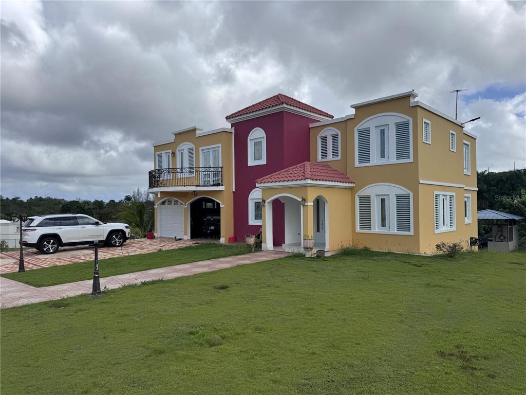 A two-story house with yellow and maroon stucco walls, a tiled roof, and a garage — Camino Los Nieves LOS NIEVES 447 INT, ISABELA, PR