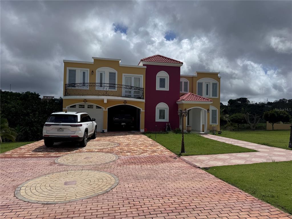 A two-story house with a yellow and maroon exterior, a tiled driveway, and a white SUV — Camino Los Nieves LOS NIEVES 447 INT, ISABELA, PR
