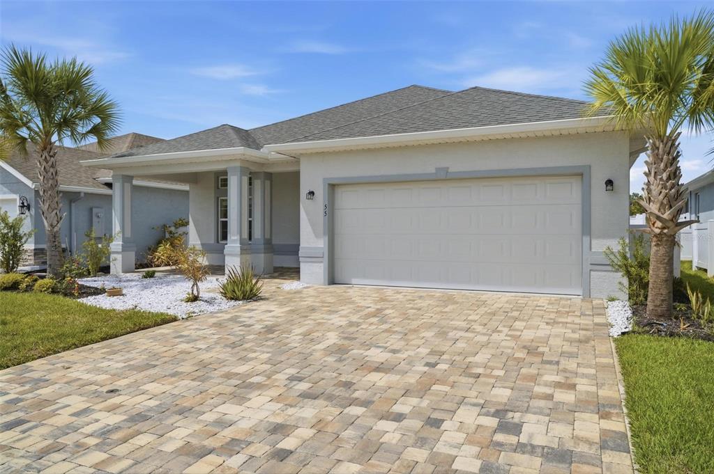 A single-story house with a paved driveway, two palm trees, and a two-car garage — 55 MATANZAS LAKES DRIVE, PALM COAST, FL