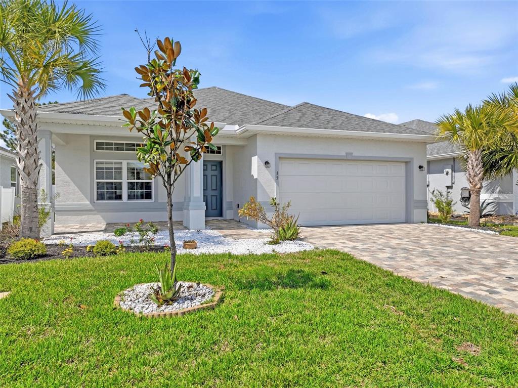 A single-story house with a white stucco exterior, a two-car garage, and a paved driveway — 55 MATANZAS LAKES DRIVE, PALM COAST, FL