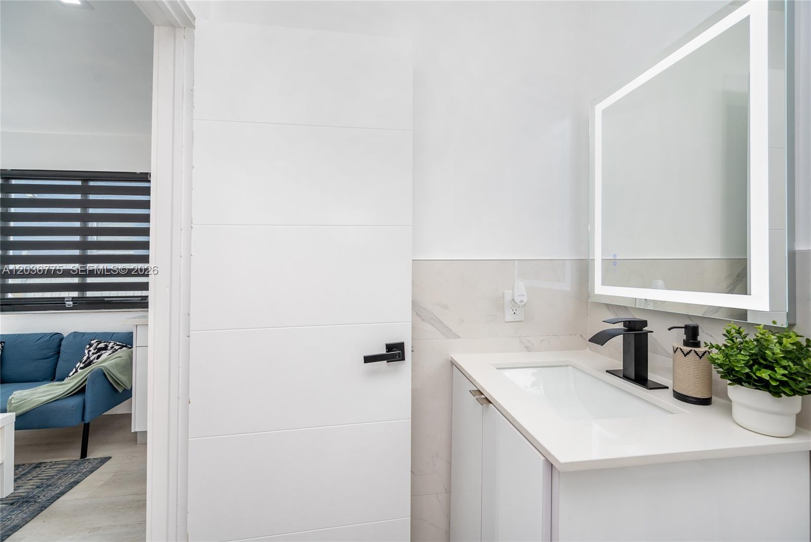 A modern bathroom features a white vanity, black faucet, and a door opening to a living area — 3016 NW 22nd Ct # 3018, Miami FL 33142, MIAMI, FL