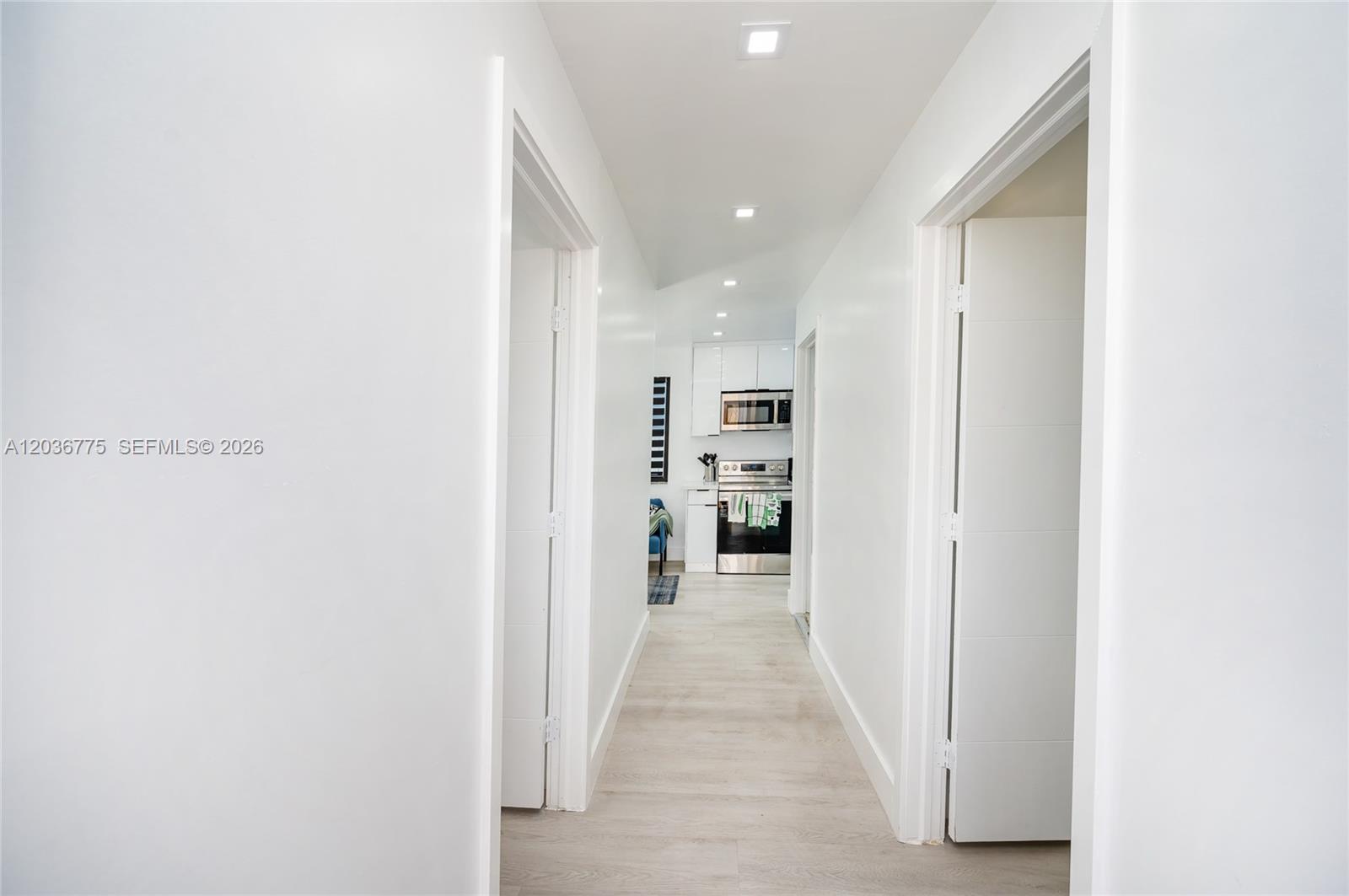 A hallway with white walls and light wood flooring leads toward a modern kitchen — 3016 NW 22nd Ct # 3018, Miami FL 33142, MIAMI, FL