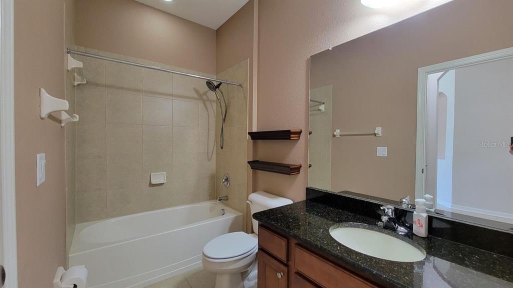 A bathroom features a shower-tub combination, a dark granite vanity, and a large wall mirror — 2229 VALTERRA VISTA WAY, VALRICO, FL