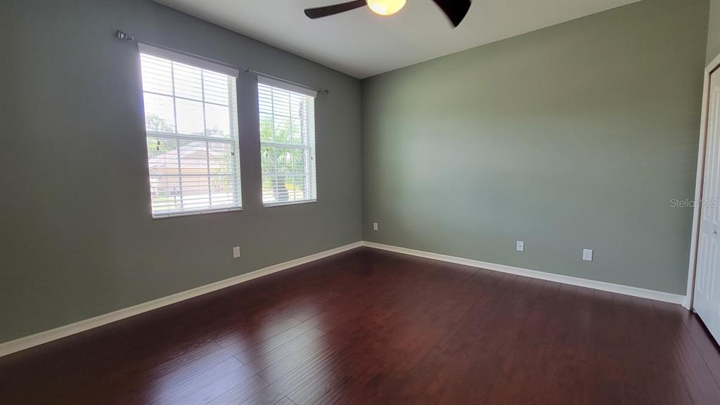 An empty bedroom features dark wood flooring, sage green walls, and two windows with blinds — 2229 VALTERRA VISTA WAY, VALRICO, FL