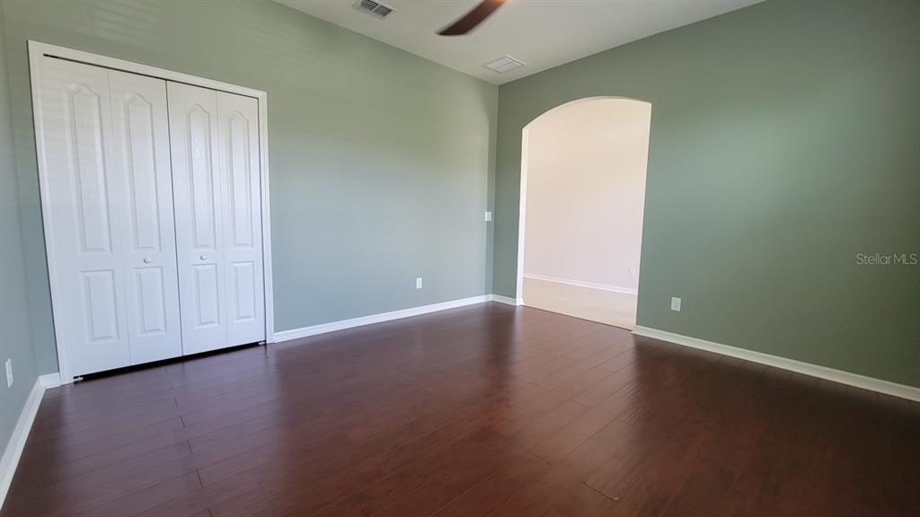An empty room features sage green walls, dark wood flooring, and a white closet door — 2229 VALTERRA VISTA WAY, VALRICO, FL