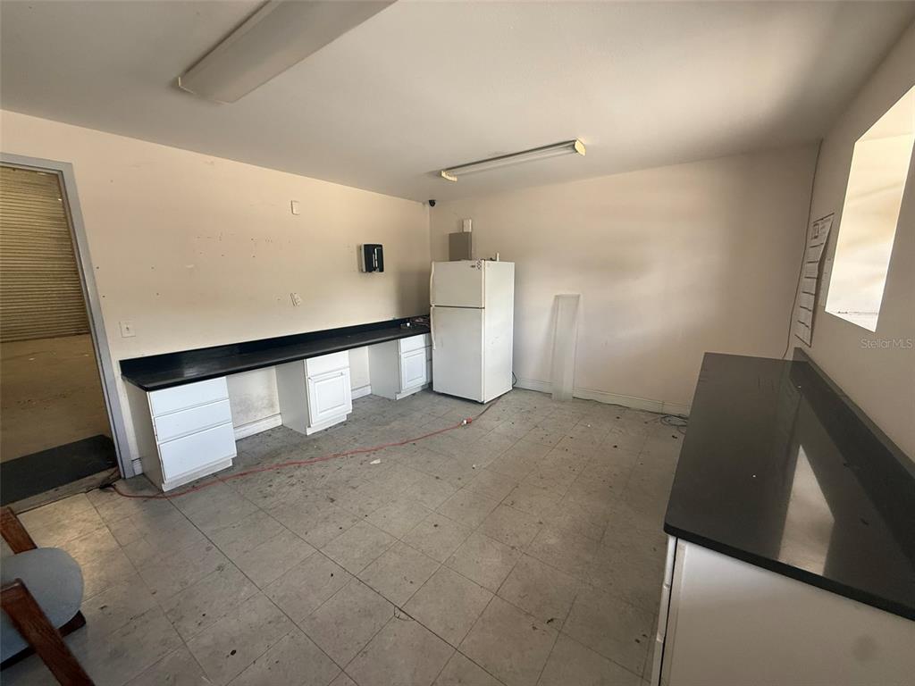 A kitchen or utility room features white cabinets, black countertops, and a white refrigerator — 4344 SE 95TH STREET UNIT 1, OCALA, FL