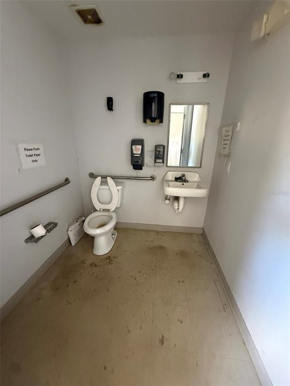 A small, utilitarian restroom features a toilet, a wall-mounted sink, and grab bars — 4344 SE 95TH STREET UNIT 1, OCALA, FL