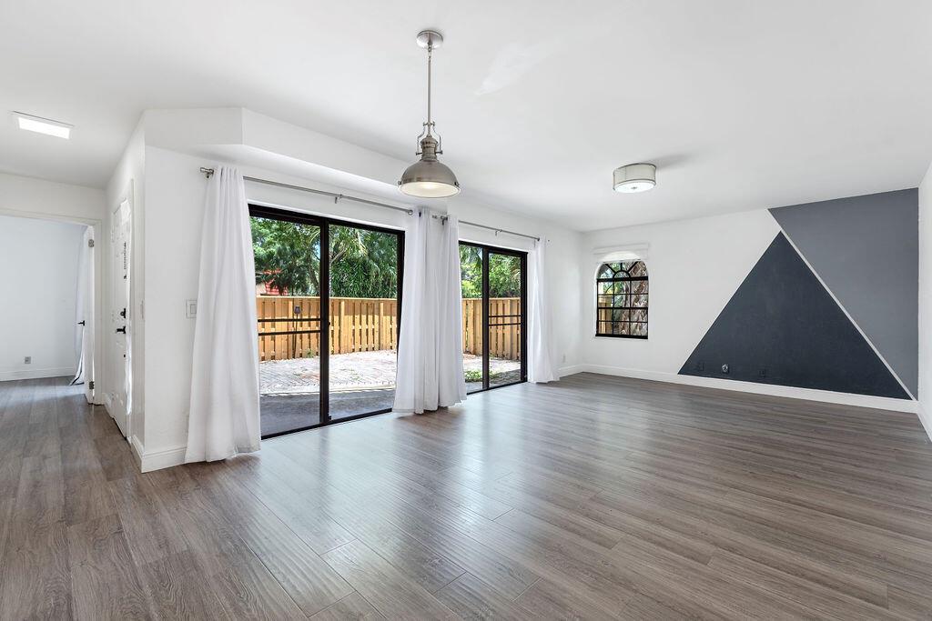 A living room features wood-look flooring, sliding glass doors, and a geometric accent wall — 8050 Severn Drive # C, Boca Raton FL 33433, BOCA RATON, FL