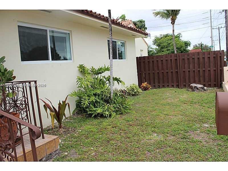 A side view of a house exterior with a lawn, landscaping, and a wooden fence — 500 NW 43rd Ct, Miami FL 33126, MIAMI, FL