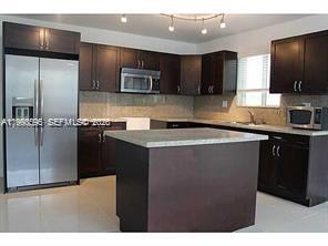 A kitchen features dark wood cabinets, stainless steel appliances, and a central island with countertops — 500 NW 43rd Ct, Miami FL 33126, MIAMI, FL