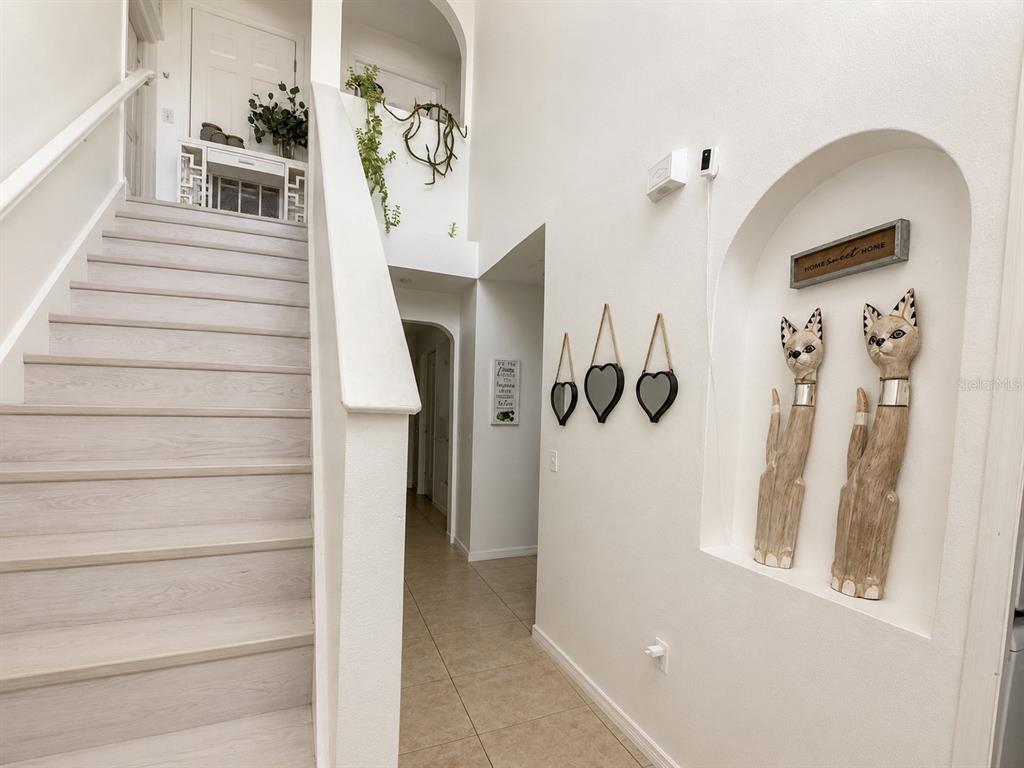 A staircase with light wood steps leads to a landing beside a decorative wall niche — 984 DERBYSHIRE DRIVE, KISSIMMEE, FL