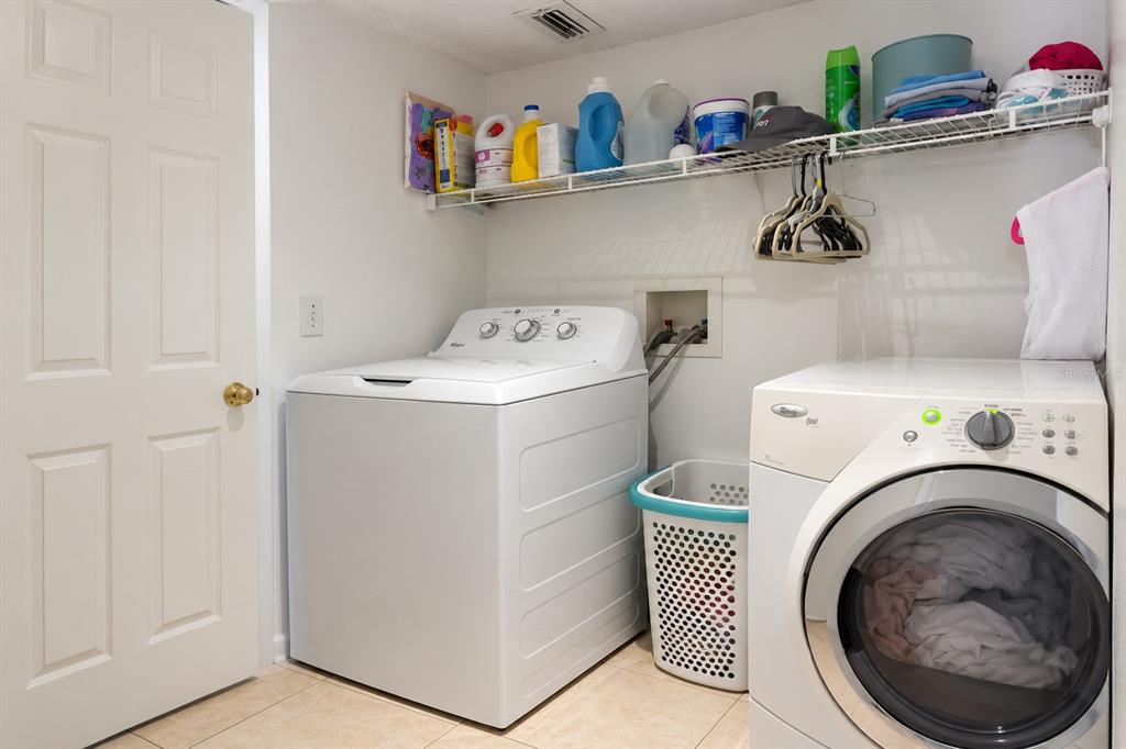 A laundry room features a top-load washer, a front-load dryer, and wire shelving above — 984 DERBYSHIRE DRIVE, KISSIMMEE, FL