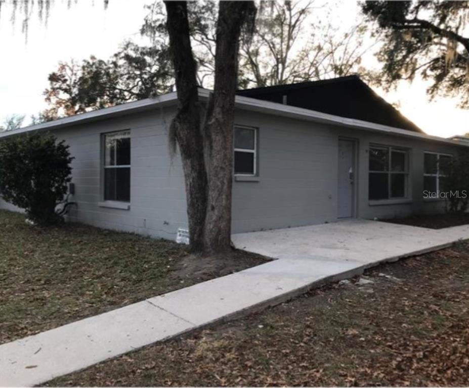 A single-story gray concrete block house with a concrete walkway leading to the front door — 3304 SW 26TH TERRACE, GAINESVILLE, FL