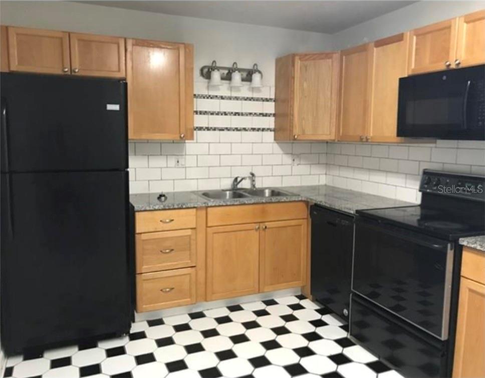 A kitchen with light wood cabinets, black appliances, a subway tile backsplash, and checkered flooring — 3304 SW 26TH TERRACE, GAINESVILLE, FL