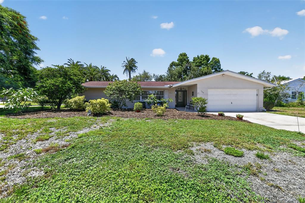 A side view of a house exterior featuring a white garage door and beige stucco walls — 100 59TH AVENUE S, ST PETERSBURG, FL