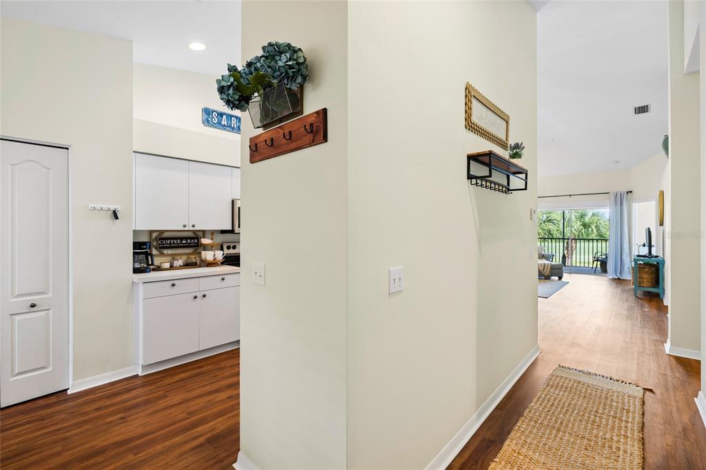 A hallway leads to a kitchen with white cabinets and a view of a balcony — 5231 MAHOGANY RUN AVENUE UNIT 325, SARASOTA, FL