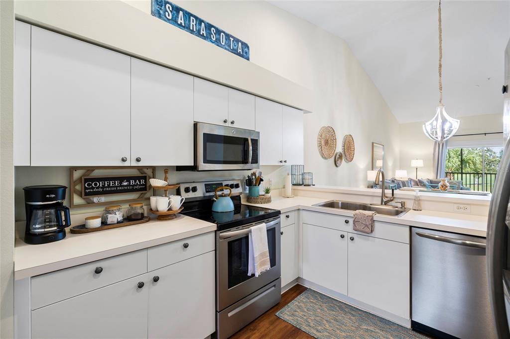 A kitchen with white cabinets, stainless steel appliances, and a coffee bar area — 5231 MAHOGANY RUN AVENUE UNIT 325, SARASOTA, FL