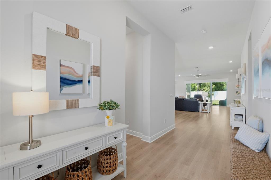 A bright entryway with a white console table leads into an open-concept living area — 7530 ASHBROOKE PINE LOOP, ODESSA, FL