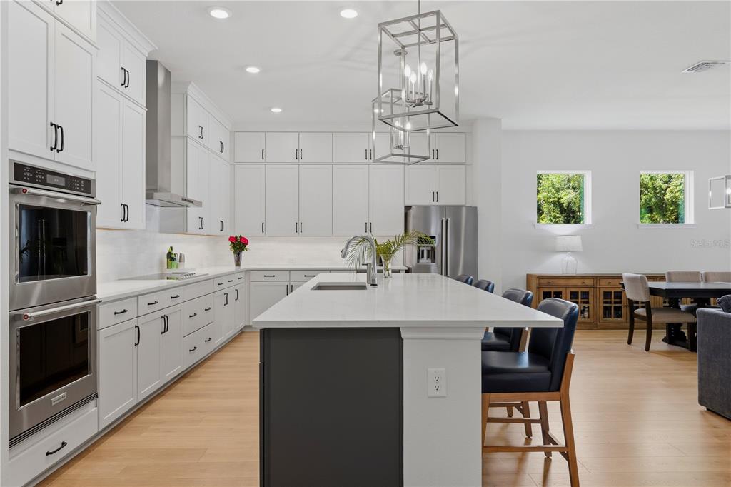 A modern kitchen features white cabinetry, a large gray island, and stainless steel appliances — 7530 ASHBROOKE PINE LOOP, ODESSA, FL