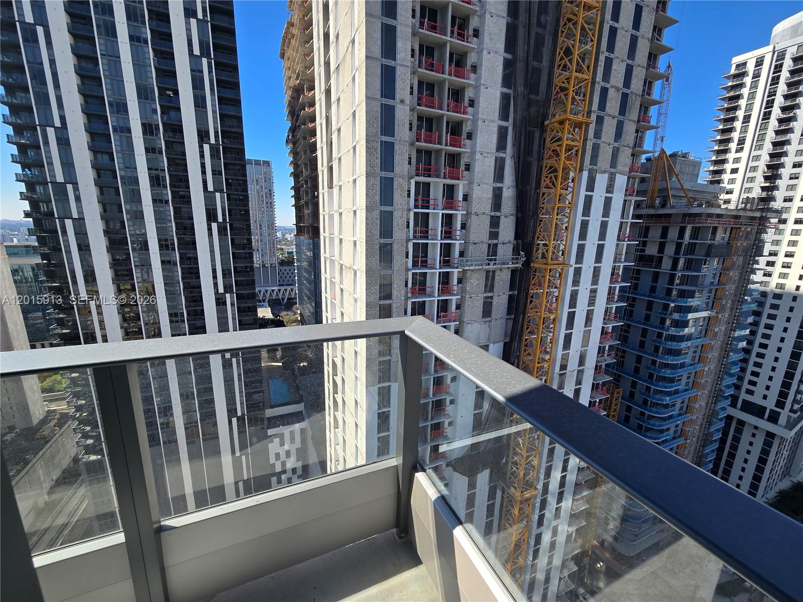 A balcony with a glass railing overlooks several high-rise buildings under construction — 121 NE 5 ST # 2908, Miami FL 33132, MIAMI, FL
