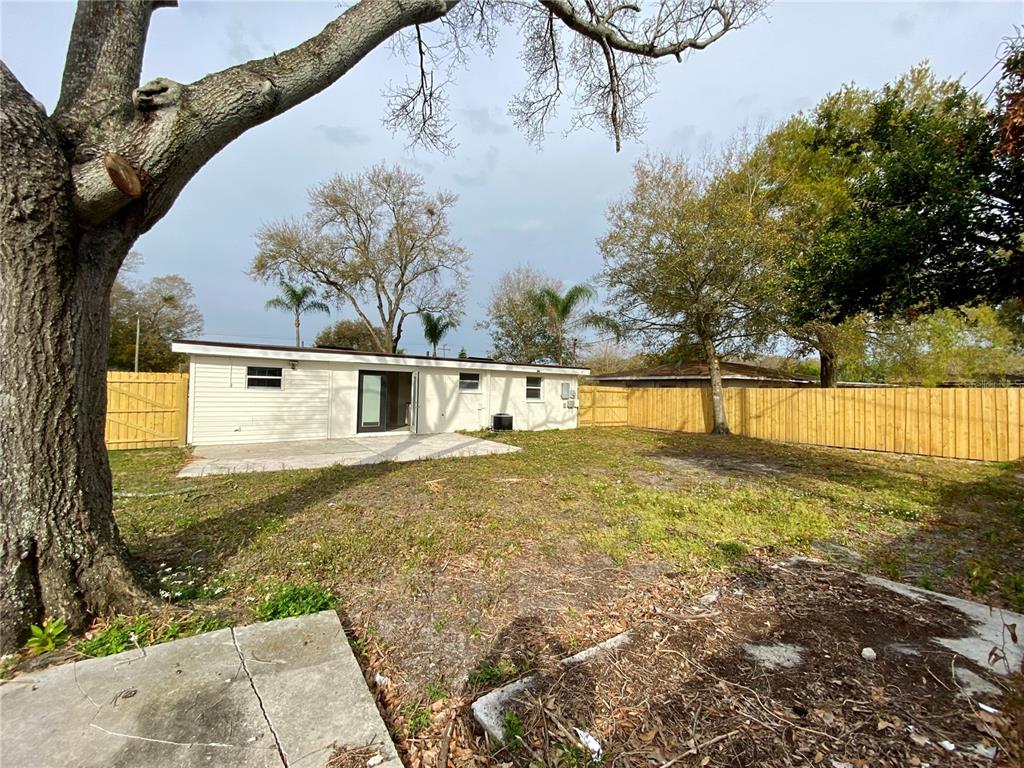 A backyard view showing a white house with a patio and a wooden fence — 1212 WINDERMERE WAY, TAMPA, FL