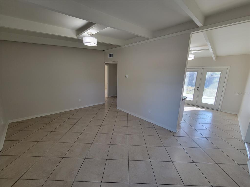 An interior view shows a tiled room with white walls, exposed ceiling beams, and French doors — 1212 WINDERMERE WAY, TAMPA, FL