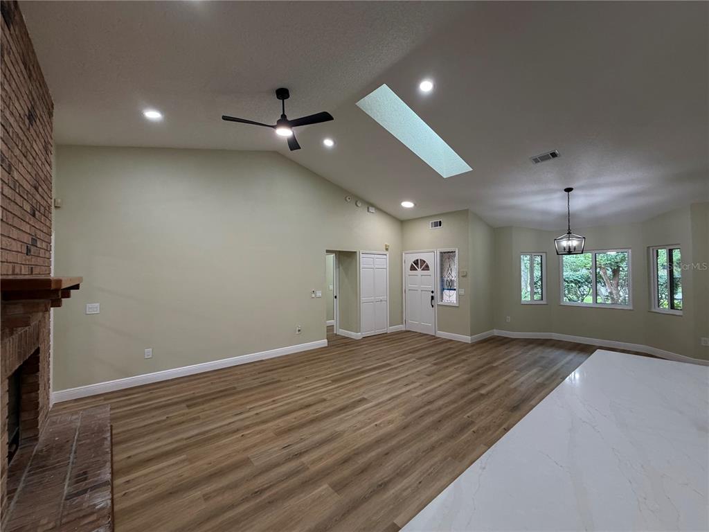 A kitchen island with a stainless steel sink and dishwasher faces a brick fireplace wall — 329 SUN OAKS COURT, LAKE MARY, FL