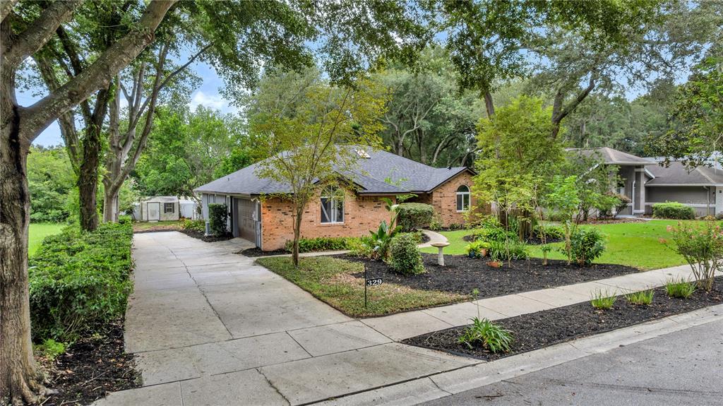 A single-story brick house with a concrete driveway and a landscaped front yard — 329 SUN OAKS COURT, LAKE MARY, FL