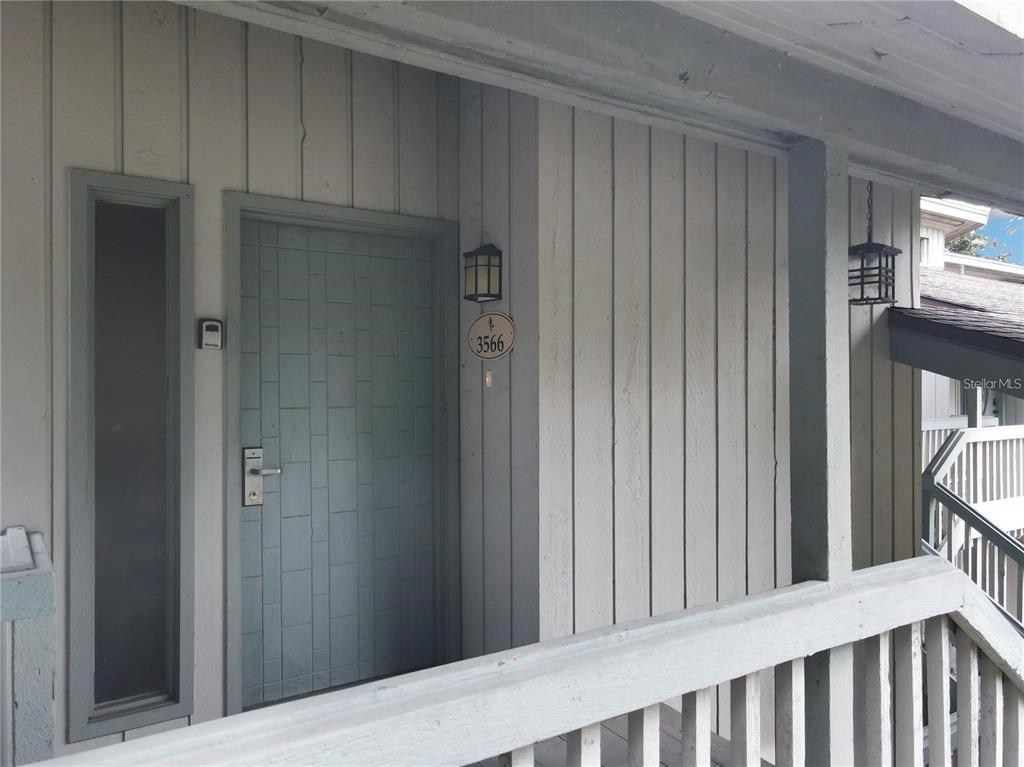 A light blue front door with a house number plaque sits on a covered porch — 3566 CAMELOT DRIVE UNIT 6, HAINES CITY, FL