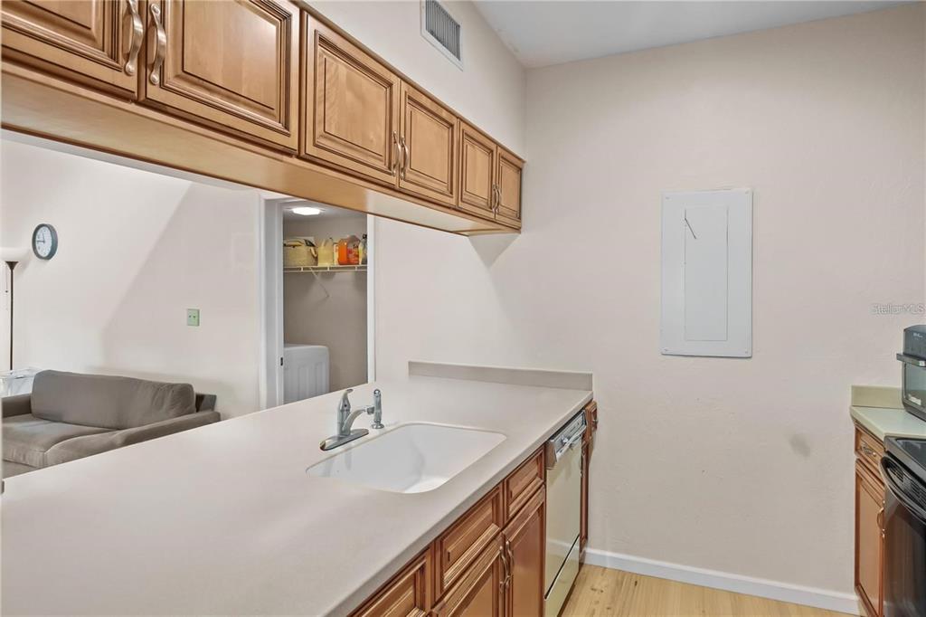 A kitchen features wood cabinets, a white sink, and a dishwasher, opening to a living area — 3566 CAMELOT DRIVE UNIT 6, HAINES CITY, FL