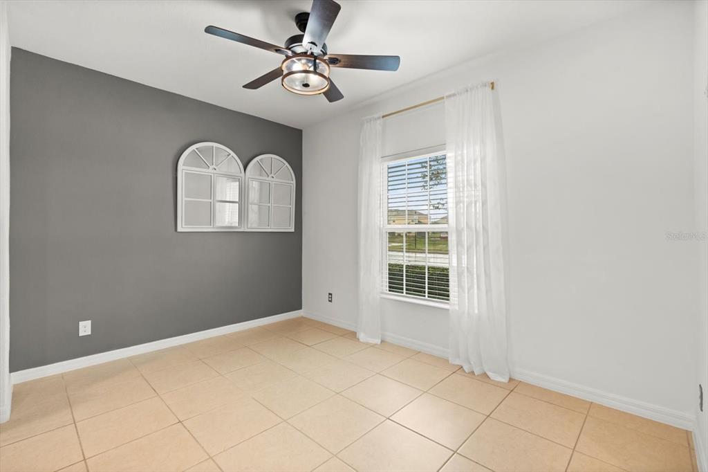 A room with light tile flooring, a gray accent wall, and a ceiling fan — 322 ANNABELLE WAY, DAVENPORT, FL