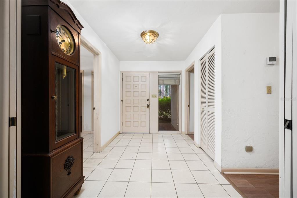 An entryway features white tile flooring, a grandfather clock, and a white front door — 412 NW 46TH STREET, GAINESVILLE, FL