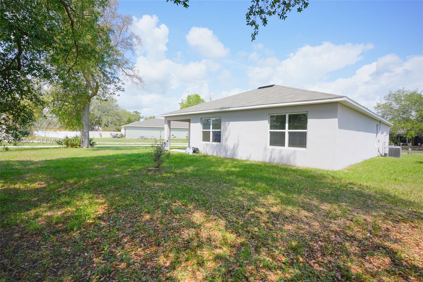 The exterior of a light-colored, single-story house features a small covered patio and lawn — 660 COTULLA Dr, Kissimmee FL 34758, KISSIMMEE, FL
