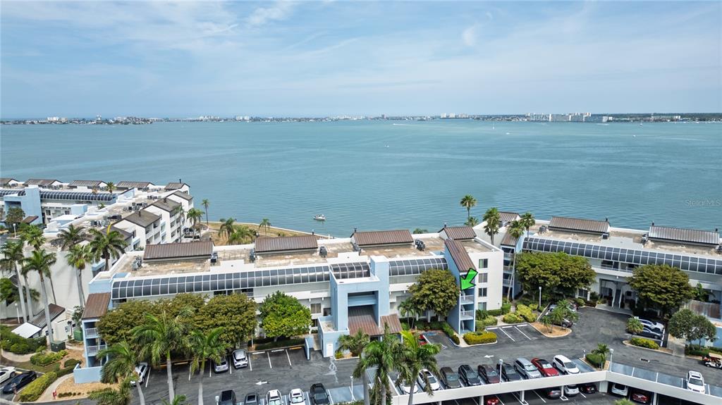An aerial view shows a multi-story blue apartment complex overlooking a large body of water — 5155 ISLA KEY BOULEVARD S UNIT 307, ST PETERSBURG, FL