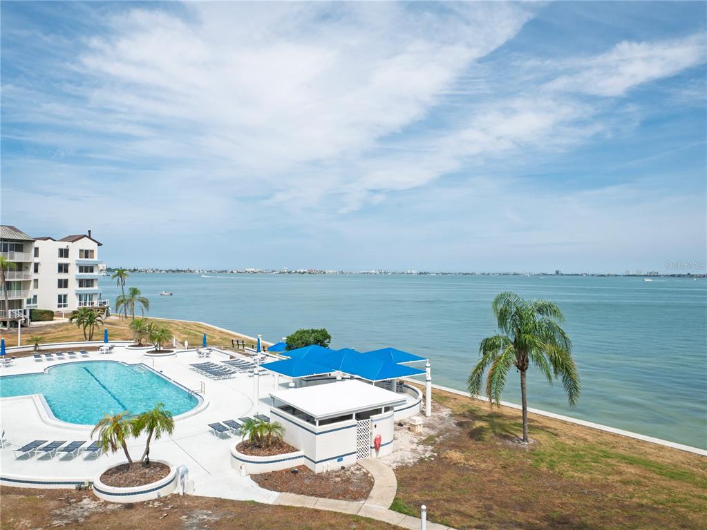 An elevated view of a waterfront swimming pool area with blue shade structures and palm trees — 5155 ISLA KEY BOULEVARD S UNIT 307, ST PETERSBURG, FL