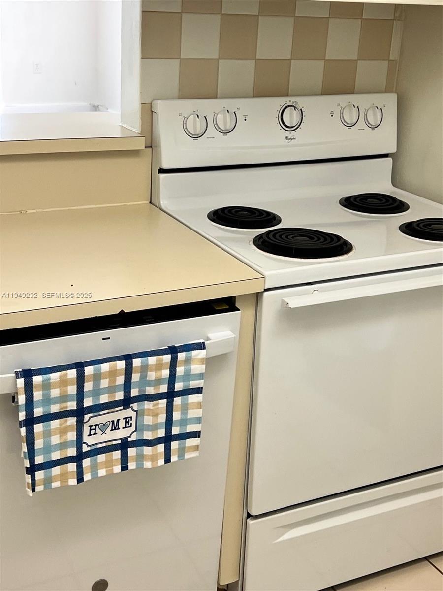 A white electric stove sits next to a dishwasher with a plaid towel — 10431 N Kendall Dr # D314, Miami FL 33176, MIAMI, FL