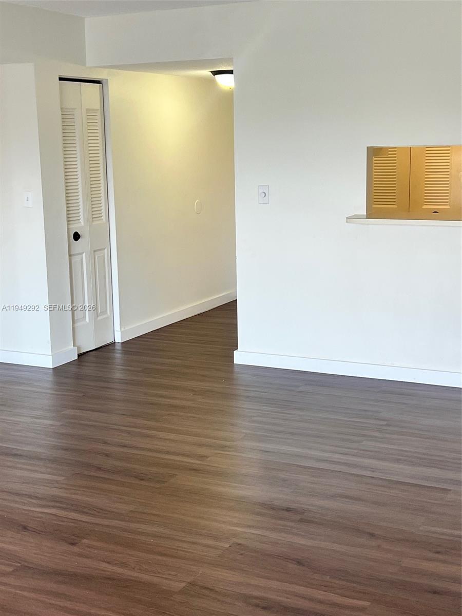 A room with wood-look flooring, white walls, a louvered closet door, and a pass-through window — 10431 N Kendall Dr # D314, Miami FL 33176, MIAMI, FL
