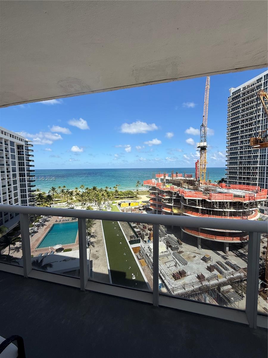 A balcony view overlooks a swimming pool, a construction site with a crane, and the ocean — 10275 Collins Ave # 921, Bal Harbour FL 33154, BAL HARBOUR, FL