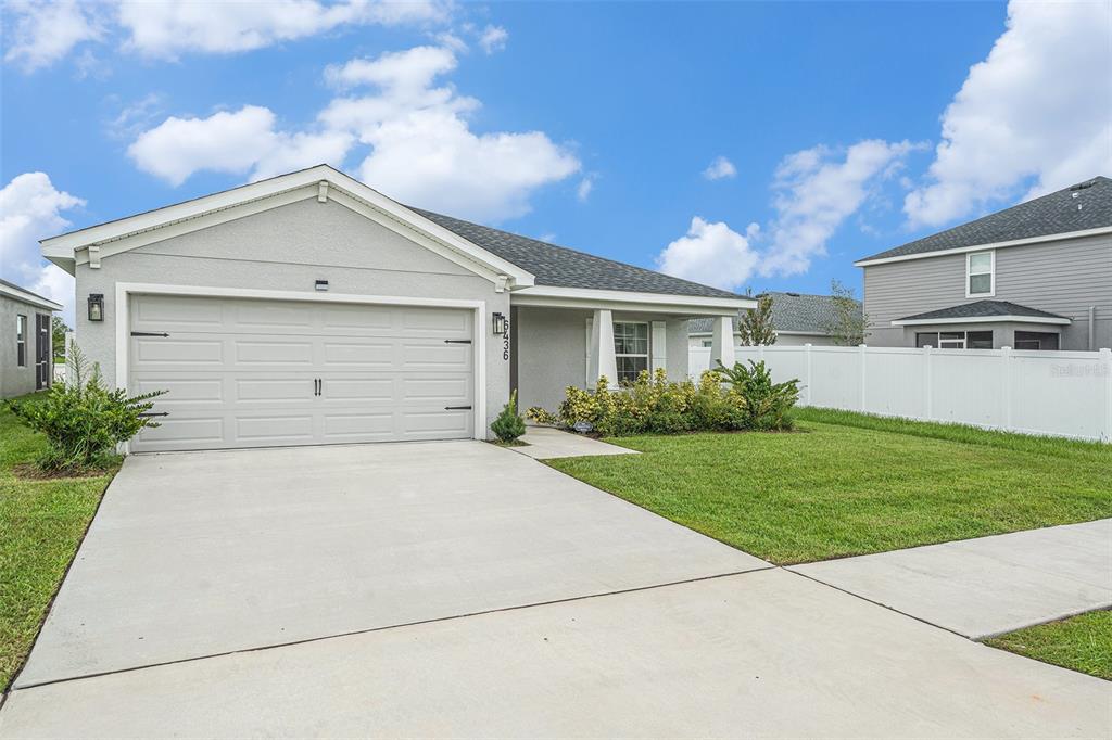 A single-story house with a gray stucco exterior, a two-car garage, and a front lawn — 6436 PEBBLEBROOKE WAY, ZEPHYRHILLS, FL