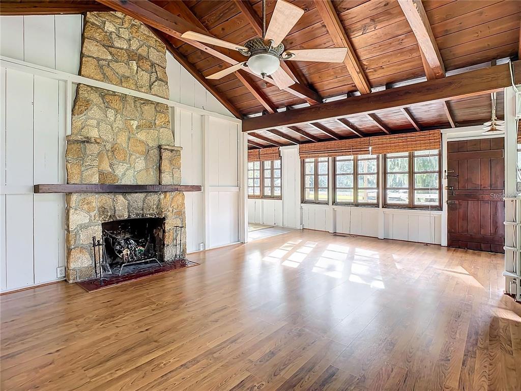 A living room features a stone fireplace, wood-plank ceiling, and light wood-look flooring — 556 STONE ISLAND ROAD, ENTERPRISE, FL