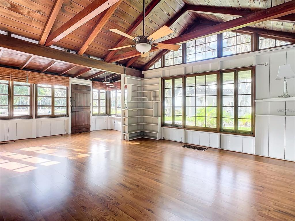 A spacious living room features a vaulted wood-beam ceiling, hardwood floors, and large windows — 556 STONE ISLAND ROAD, ENTERPRISE, FL