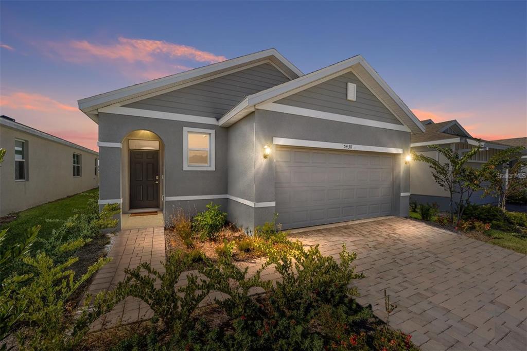 A gray single-story house with a two-car garage and a paved driveway at dusk — 5430 NW 46TH LANE, OCALA, FL