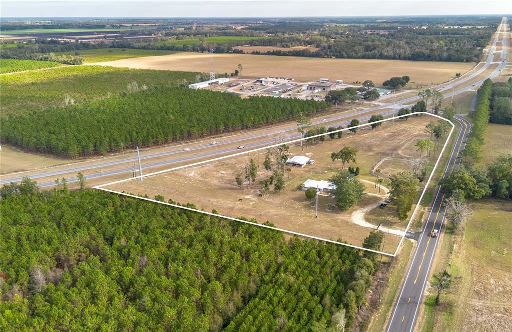 An aerial view shows a rural property with a house, outbuildings, and surrounding forest — 1415 SE 4TH AVENUE, CHIEFLAND, FL