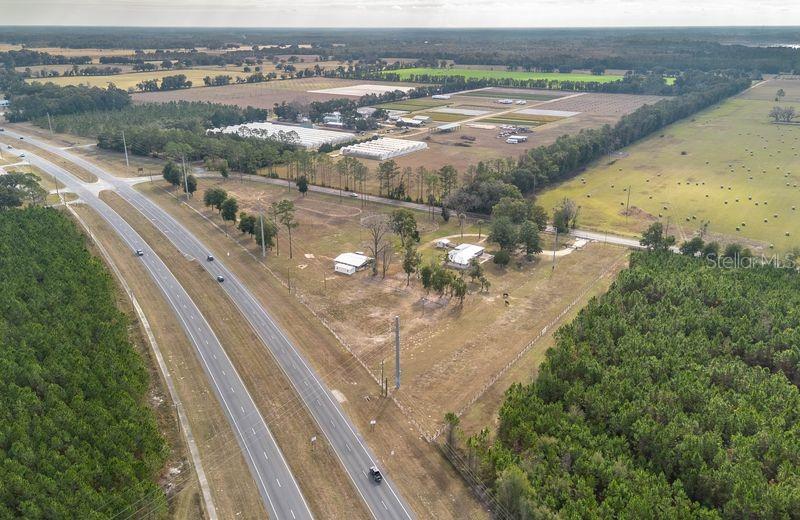 An aerial view shows a rural property with a house, outbuildings, and surrounding agricultural land — 1415 SE 4TH AVENUE, CHIEFLAND, FL