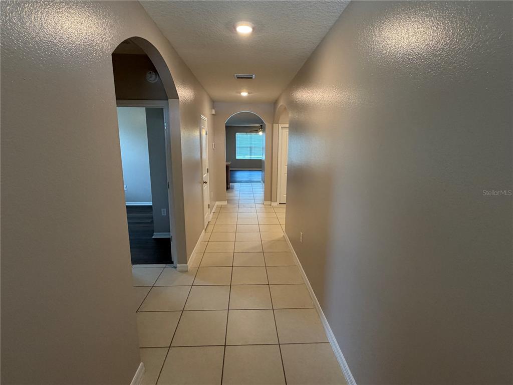 A tiled hallway features arched doorways leading to other rooms with light-colored walls — 2822 NE 44TH ROAD, OCALA, FL