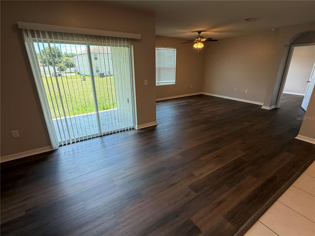An open living area features dark wood-look flooring, a ceiling fan, and sliding glass doors — 2822 NE 44TH ROAD, OCALA, FL