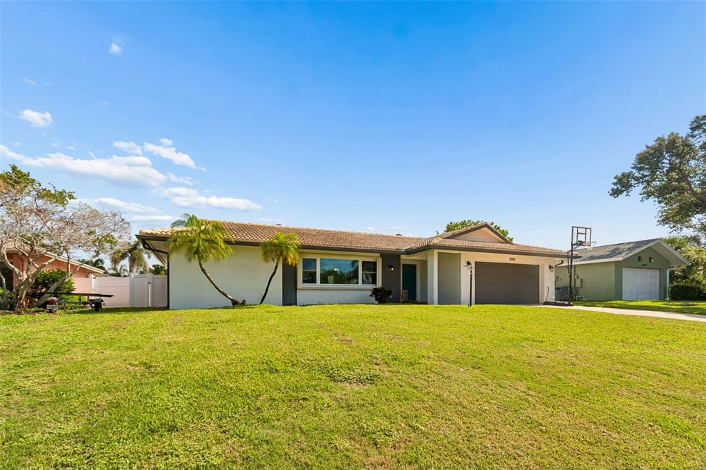 A single-story house with a gray garage, a large lawn, and palm trees — 13901 88TH TERRACE, SEMINOLE, FL